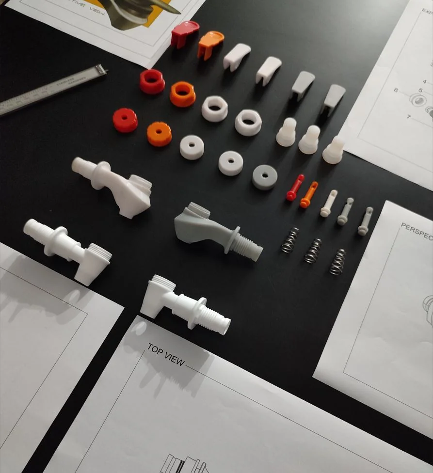 Full set of 3D-printed Sweep tap prototype parts laid out on a black desk next to the exploded-view spec drawing and digital calipers, including the lever, valve stem, gaskets and springs.